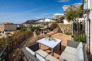 An outdoor patio with wicker furniture, a table with a vase of flowers, and umbrellas. - LA TARTANA HOTEL BOUTIQUE (Almunecar)
