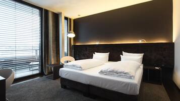 A modern hotel room with a large bed, a desk, and a chair.