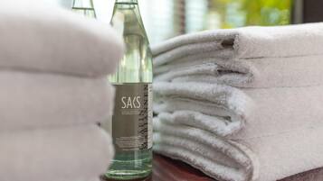 A stack of white towels and two clear glass bottles with labels.