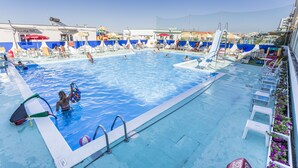 A swimming pool with multiple lanes, lounge chairs, and umbrellas. - Hotel Stella Maris (Cesenatico)