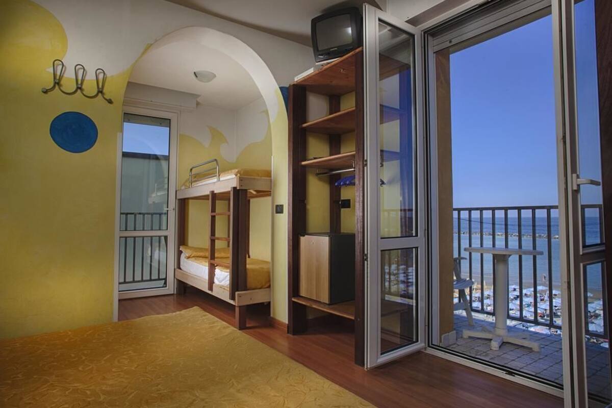 Una habitación con literas, una mesita pequeña y un balcón con vista a la playa.
