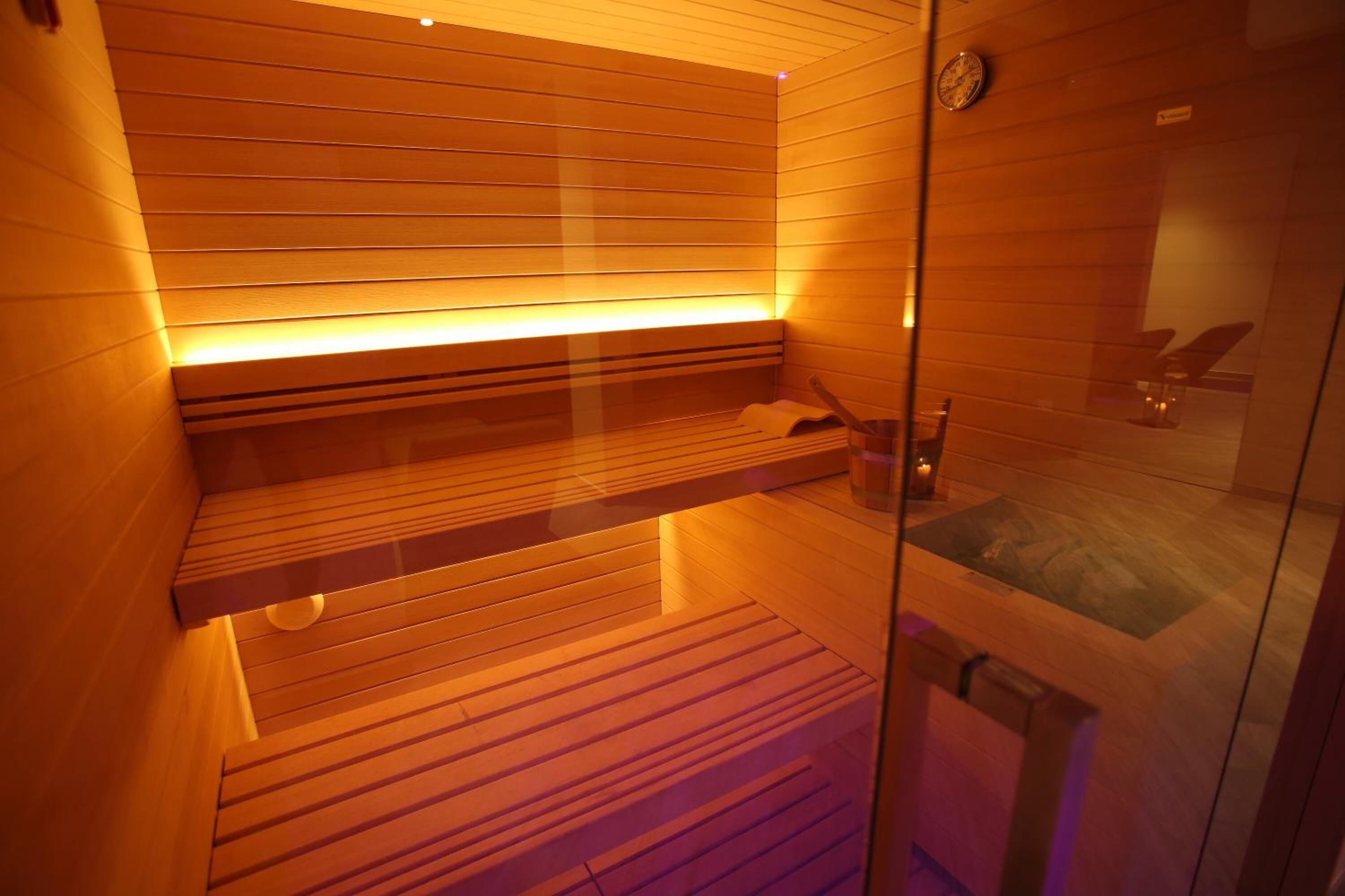 A sauna room with wooden benches and a glass partition.