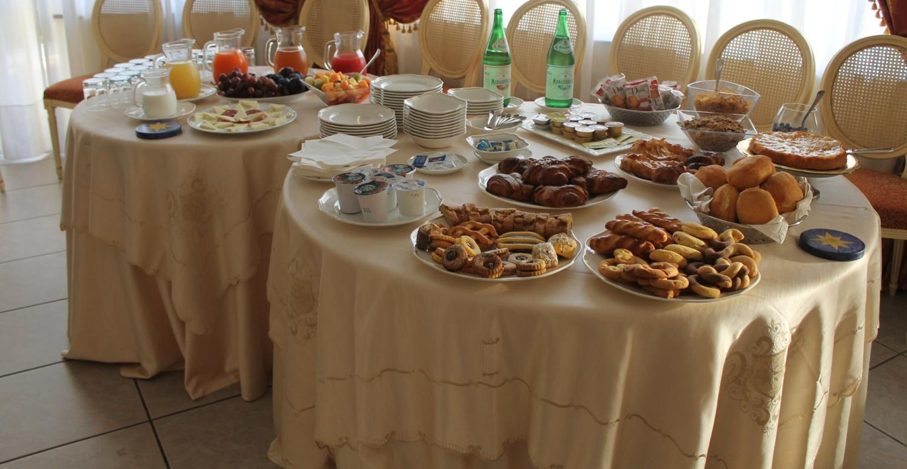 A breakfast buffet with various pastries, fruits, and beverages on a table.