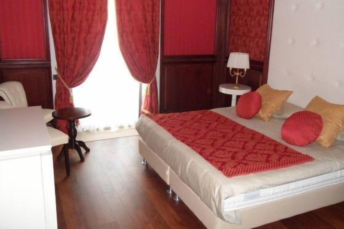A bedroom with a bed, a bedside table, a lamp, and a chair.