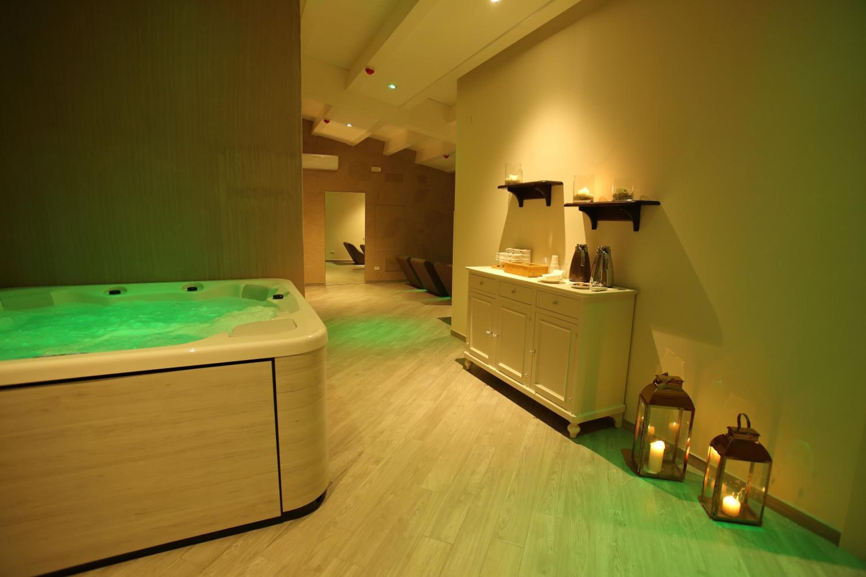Un cuarto de spa con bañera de hidromasaje, tocador con espejo y dos faroles en la pared.