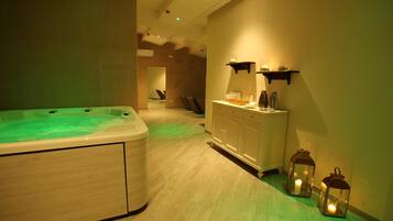 A spa room with a hot tub, a vanity with a mirror, and two wall-mounted lanterns.