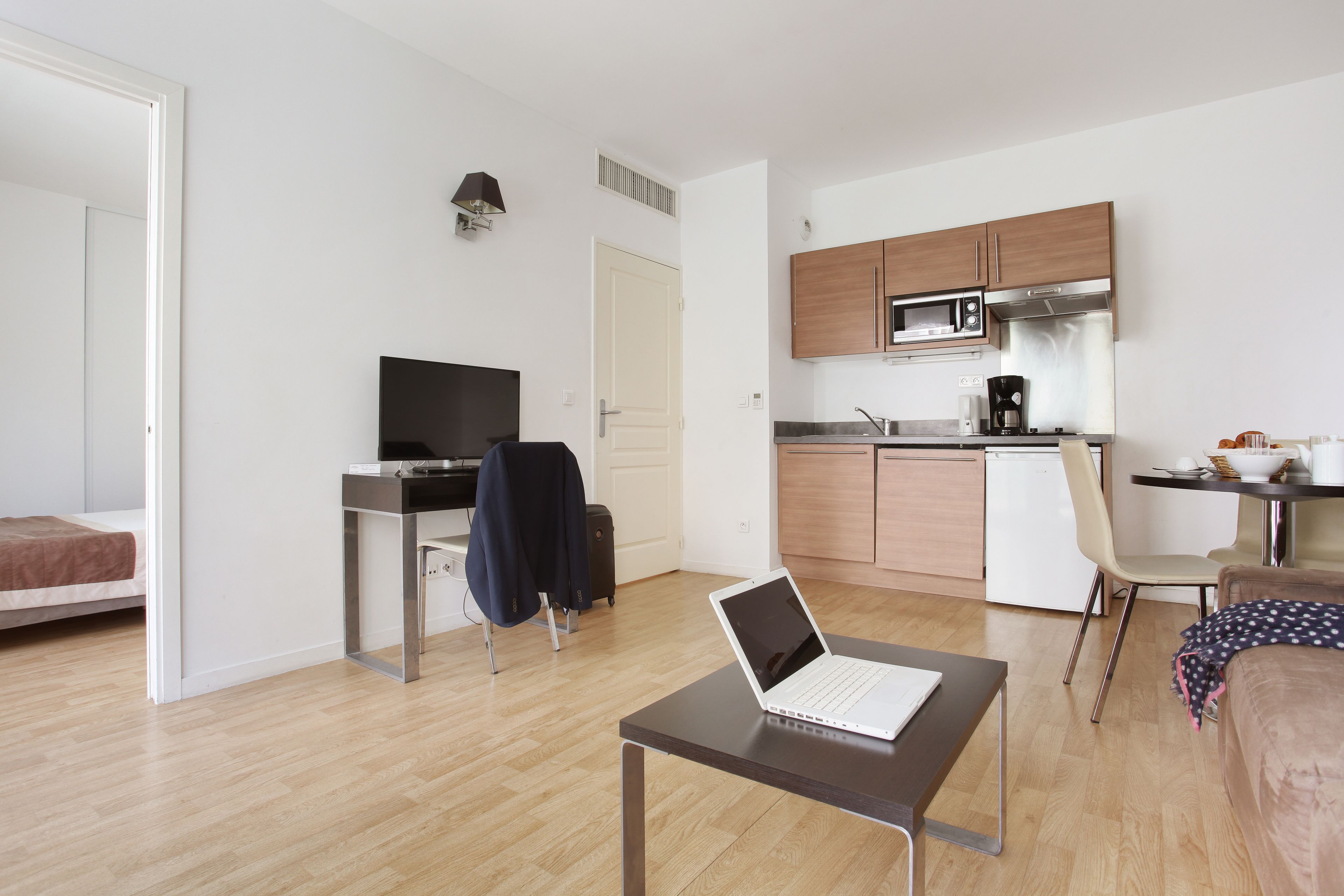 Een modern appartement met een kitchenette, een eetgedeelte en een slaapkamer.