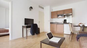 Een modern appartement met een kitchenette, een eetgedeelte en een slaapkamer.