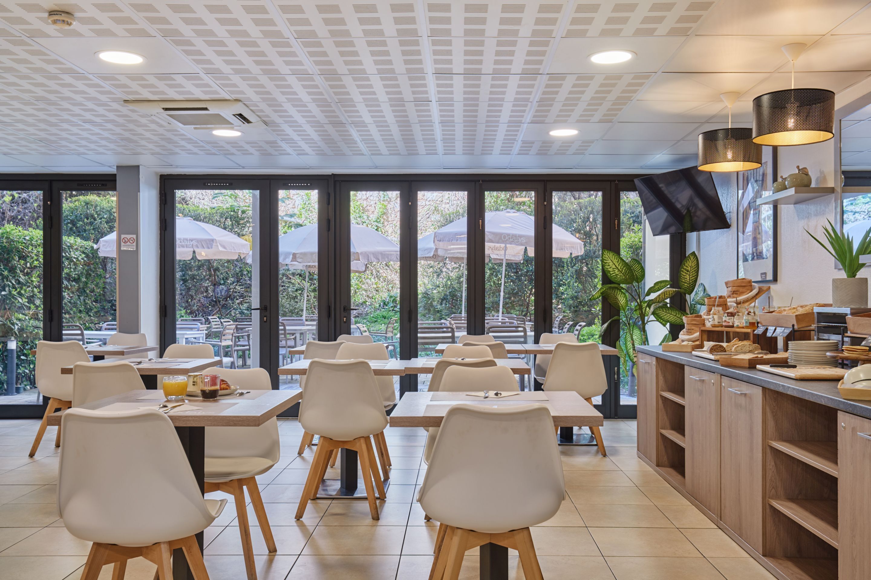 Un restaurante con mesas en el interior, amplias ventanas y una barra con equipo de cocina.