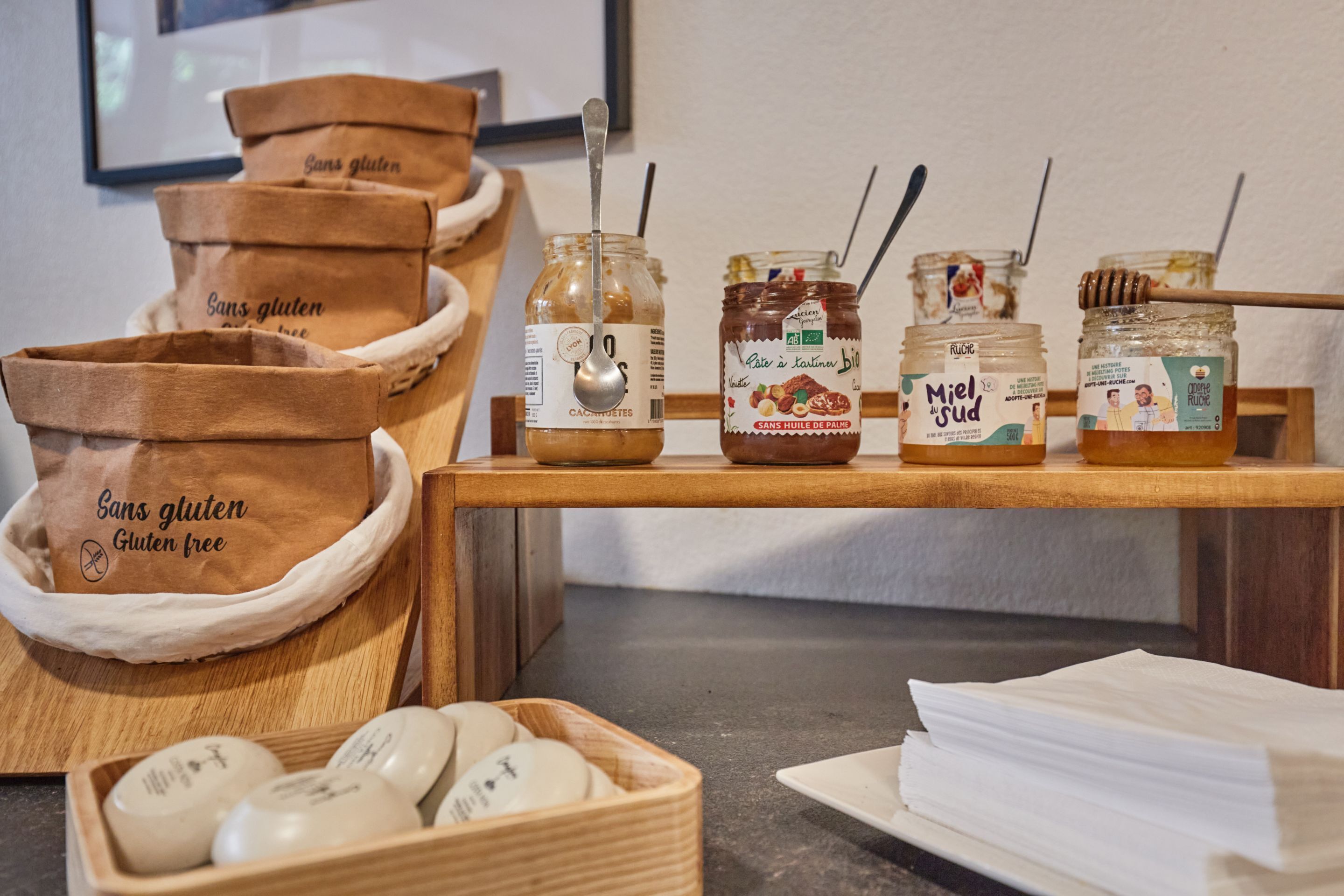 Bolsas sin gluten, tarros de miel y una bandeja de huevos sobre una mesa de madera.