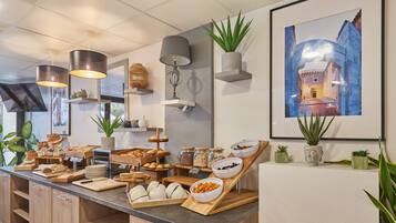 A breakfast buffet with various food items, a Buddha statue, and a framed painting on the wall.