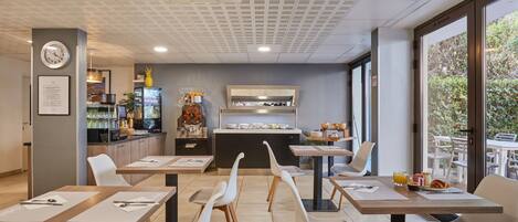 A modern restaurant with tables, chairs, a counter, and a view of greenery outside.