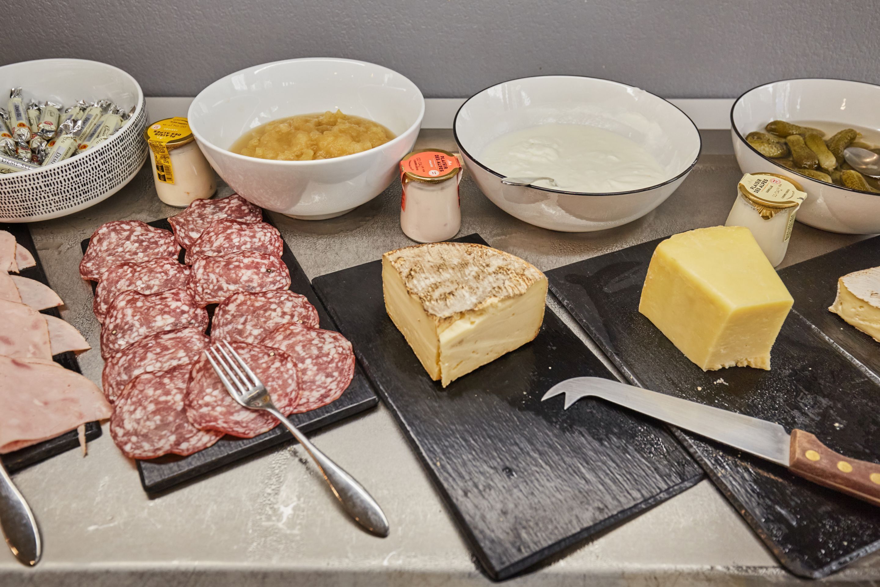 Une variété de fromages, de charcuteries et de condiments sont disposés sur une table.