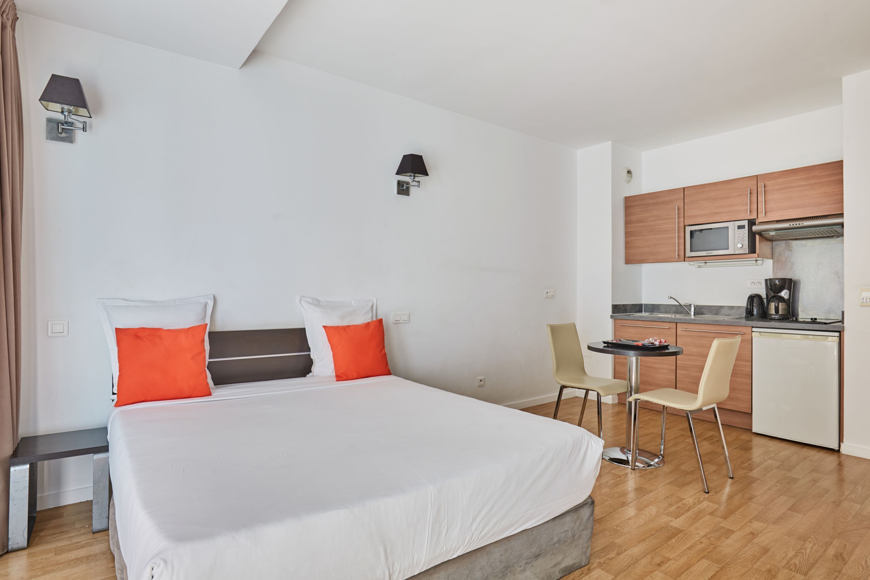 Een hotelkamer met een bed, een bureau, een stoel, een magnetron en een koffiezetapparaat.