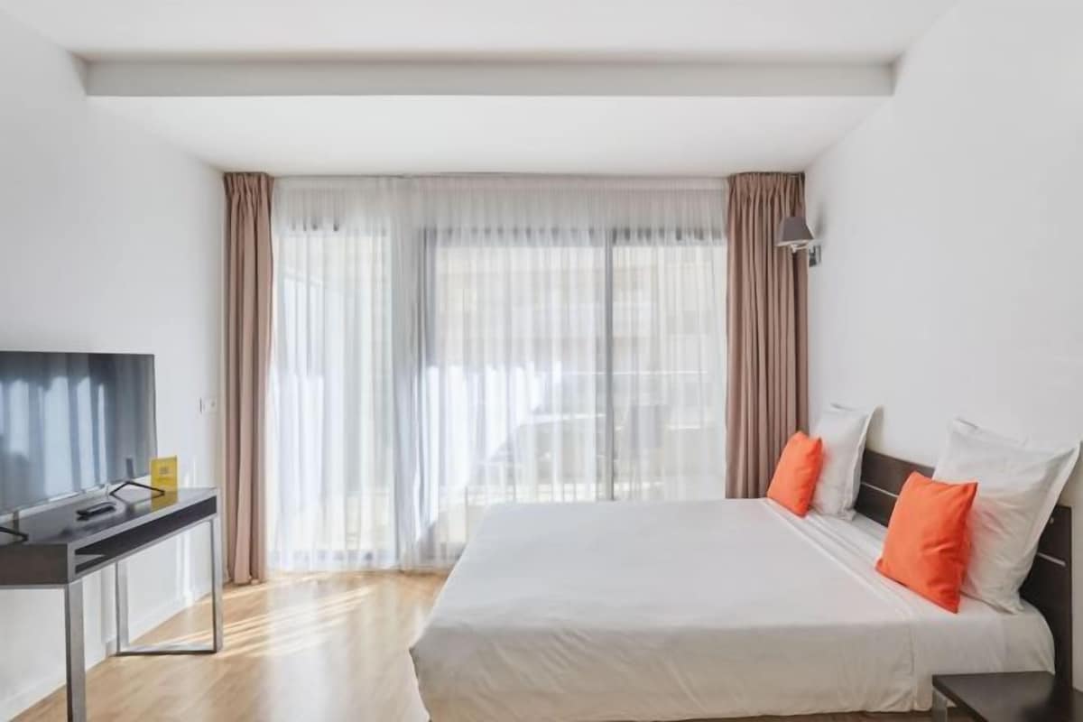 A hotel room with a large bed, a desk, and a TV.