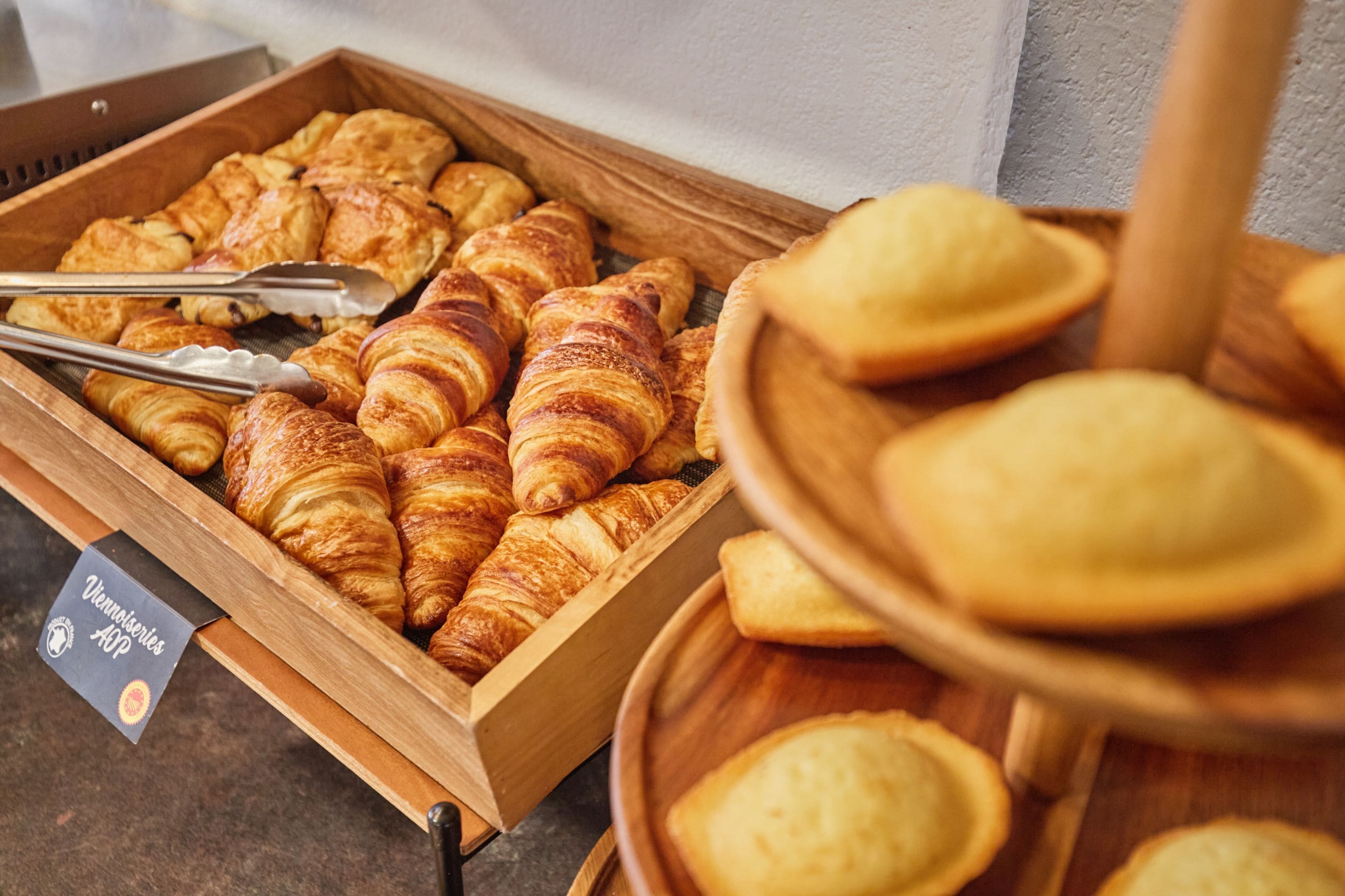 Una bandeja de madera con diversos pasteles, incluyendo croissants y pequeños panes.