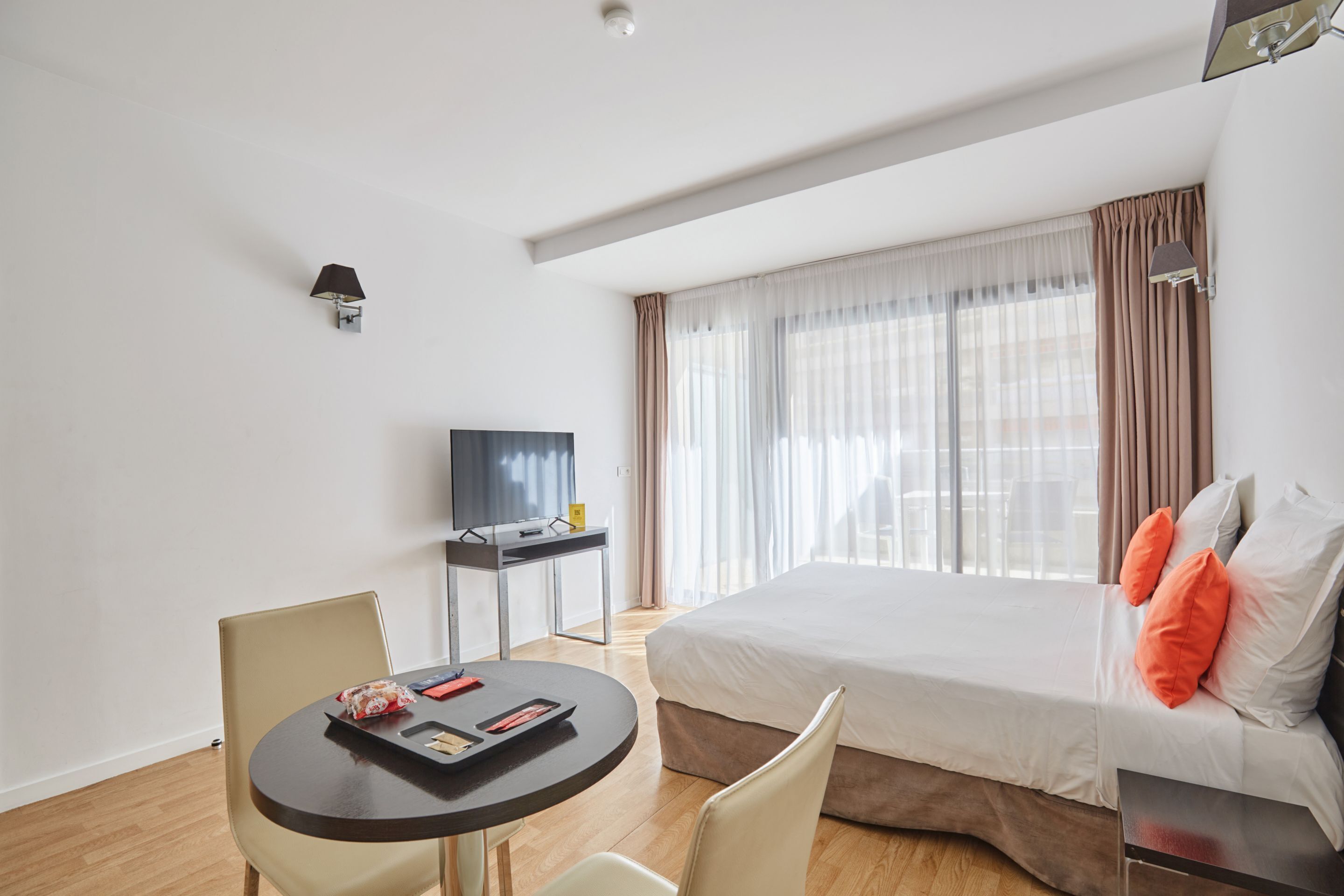 A hotel room with a bed, a desk, a chair, and a TV.