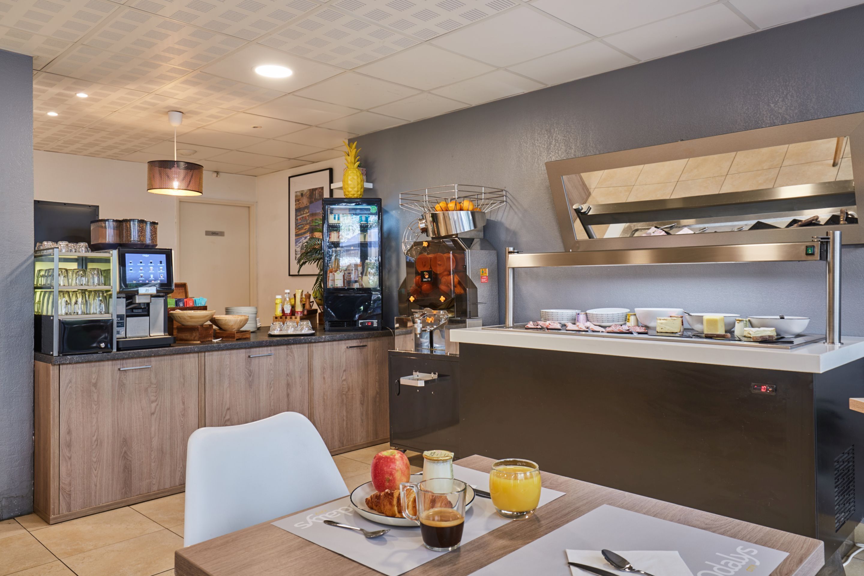 A modern breakfast bar with a coffee machine, fruit bowl, and a variety of breakfast items.
