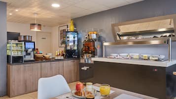 Una moderna colazione a buffet con macchina del caffè, frutta fresca e diverse opzioni per la colazione.