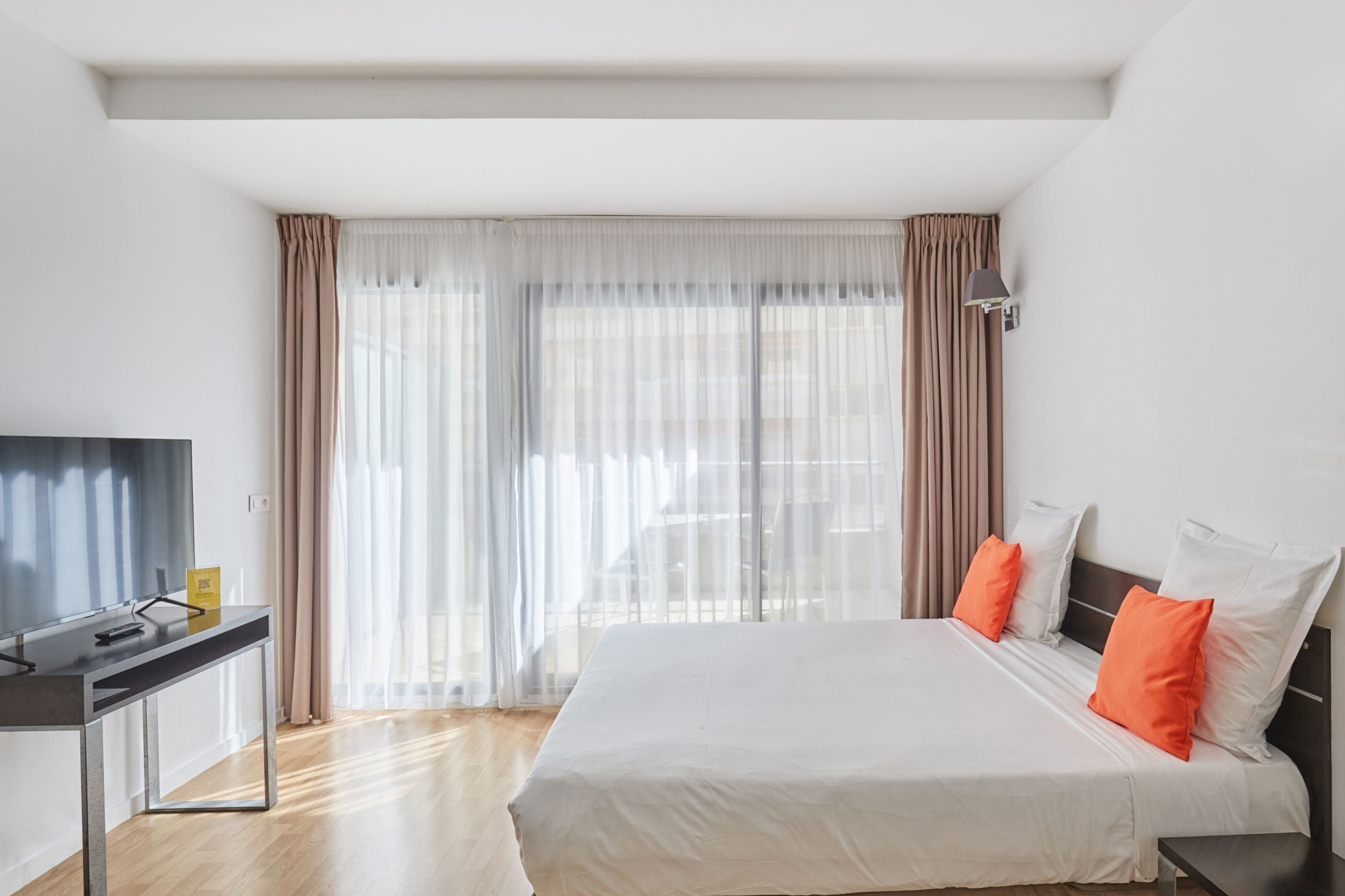 Habitació d'hotel moderna amb un llit gran, una taula de treball i una televisió.