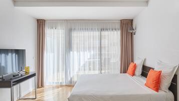Habitació d'hotel moderna amb un llit gran, una taula de treball i una televisió.