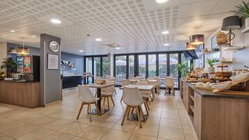 A modern restaurant with a central island, dining tables, and chairs.