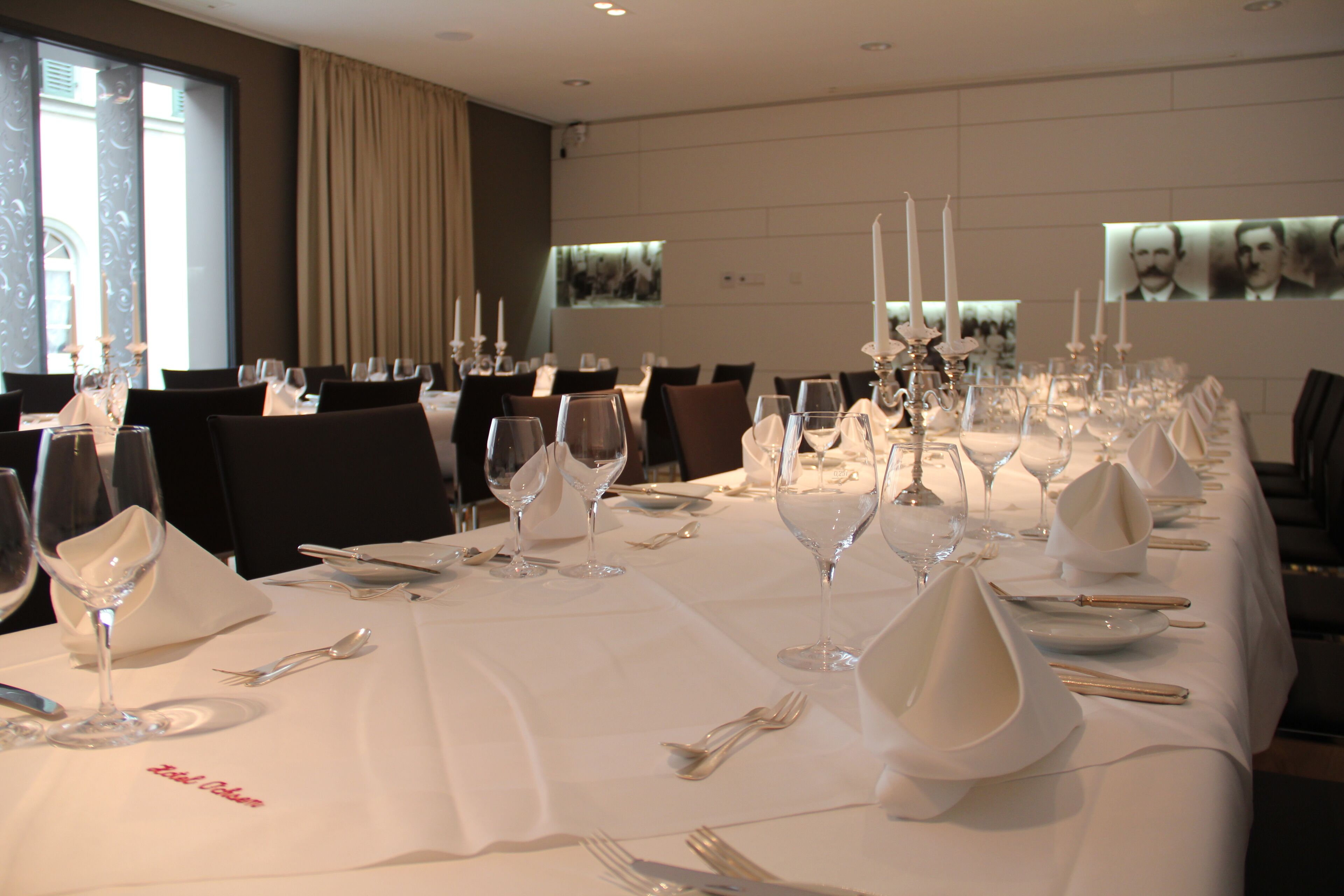 A long dining table set with multiple place settings, including wine glasses, cutlery, and napkins.