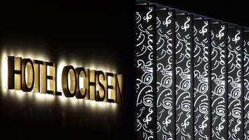 A hotel sign with the name "HOTEL OCHSEN" illuminated in gold letters.