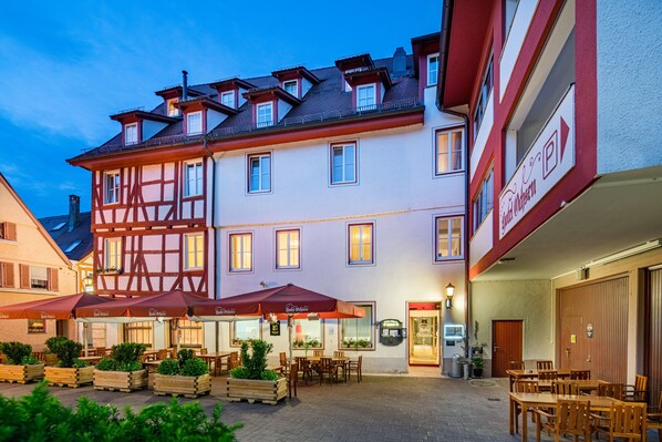 A traditional European building with a courtyard, outdoor seating, and a sign indicating a restaurant. - Hotel Ochsen (Blaubeuren)