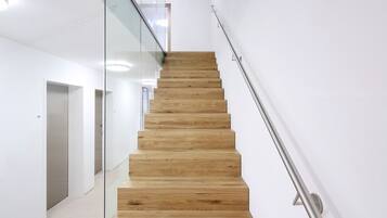 A modern staircase with wooden steps and glass railings in a minimalist interior.