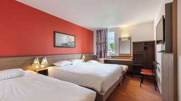 A hotel room with two beds, a wooden headboard, a desk with a chair, a mirror, and a wardrobe.
