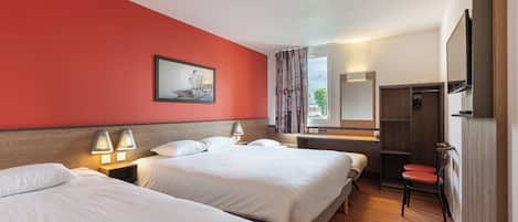 A hotel room with two beds, a wooden headboard, a desk with a chair, a mirror, and a wardrobe.