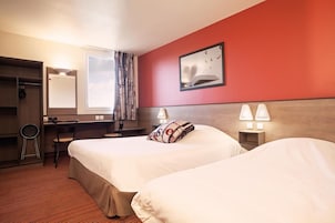A hotel room with two beds, a desk, a chair, a wardrobe, and a window with curtains.
