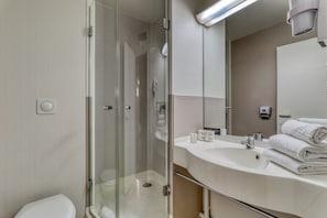 A modern bathroom with a glass-enclosed shower, a sink with toiletries, and a mirror. - Ace Hôtel Bourges (Bourges)