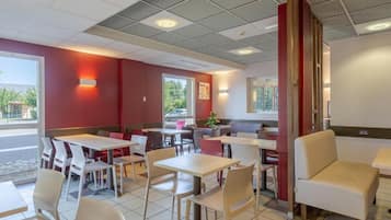 A restaurant interior with booths and tables, red walls, and a tiled floor.