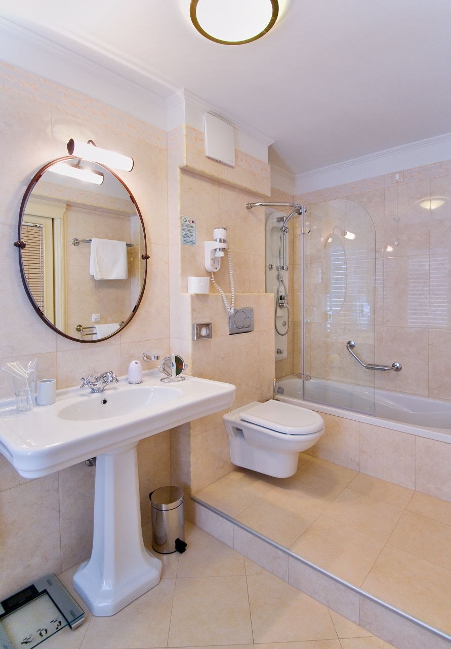 Un bagno moderno con lavabo su piedistallo, WC e cabina doccia in vetro.