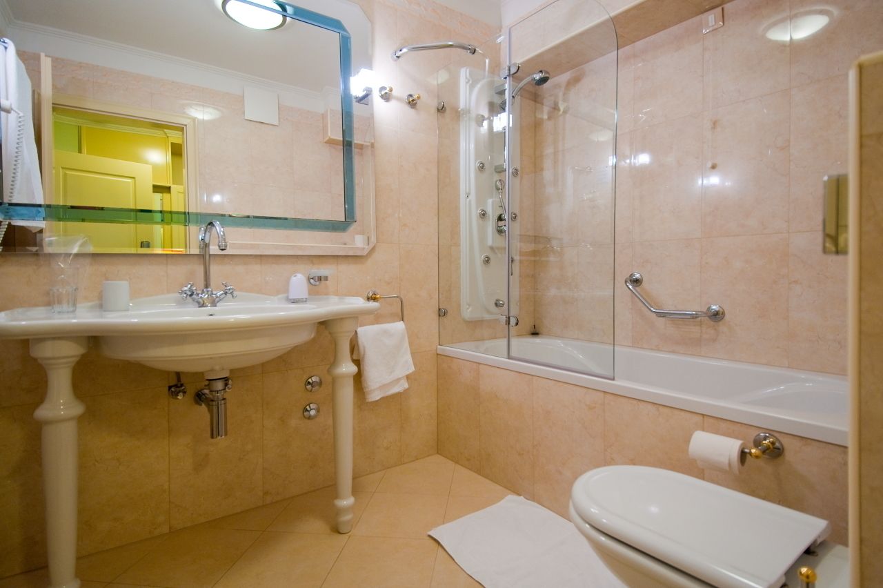 A bathroom with a sink, mirror, shower, and toilet.