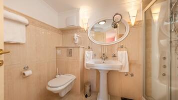 Un baño con inodoro, bidé, lavamanos y cabina de ducha de vidrio.