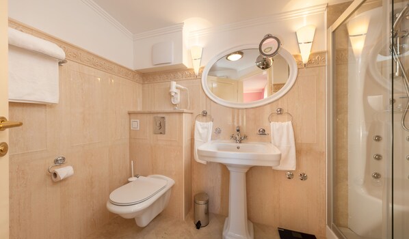 A bathroom with a toilet, bidet, sink, and glass shower enclosure.