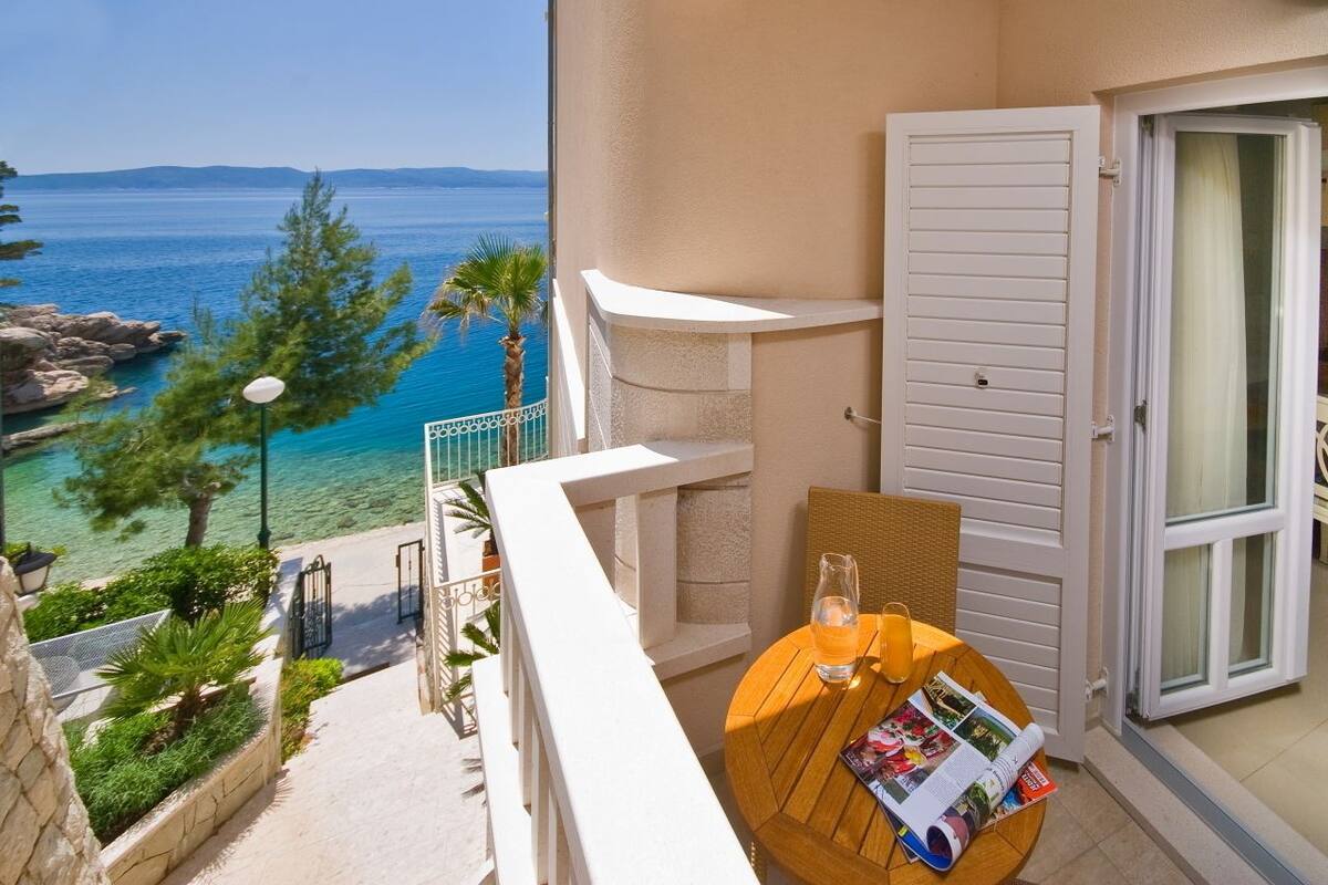 A balcony with a view of the sea, a table with a magazine, and a door.