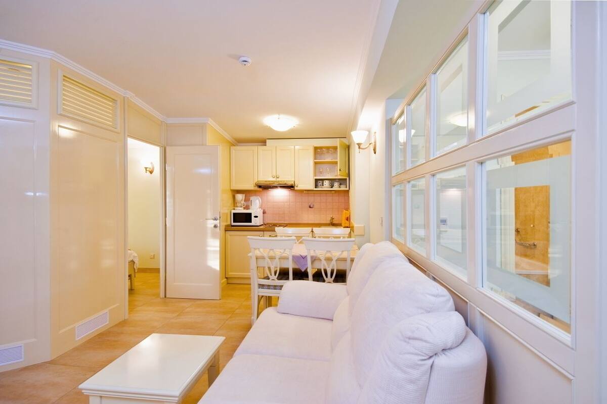 A compact living space with a kitchenette, a white sofa, and a dining area.
