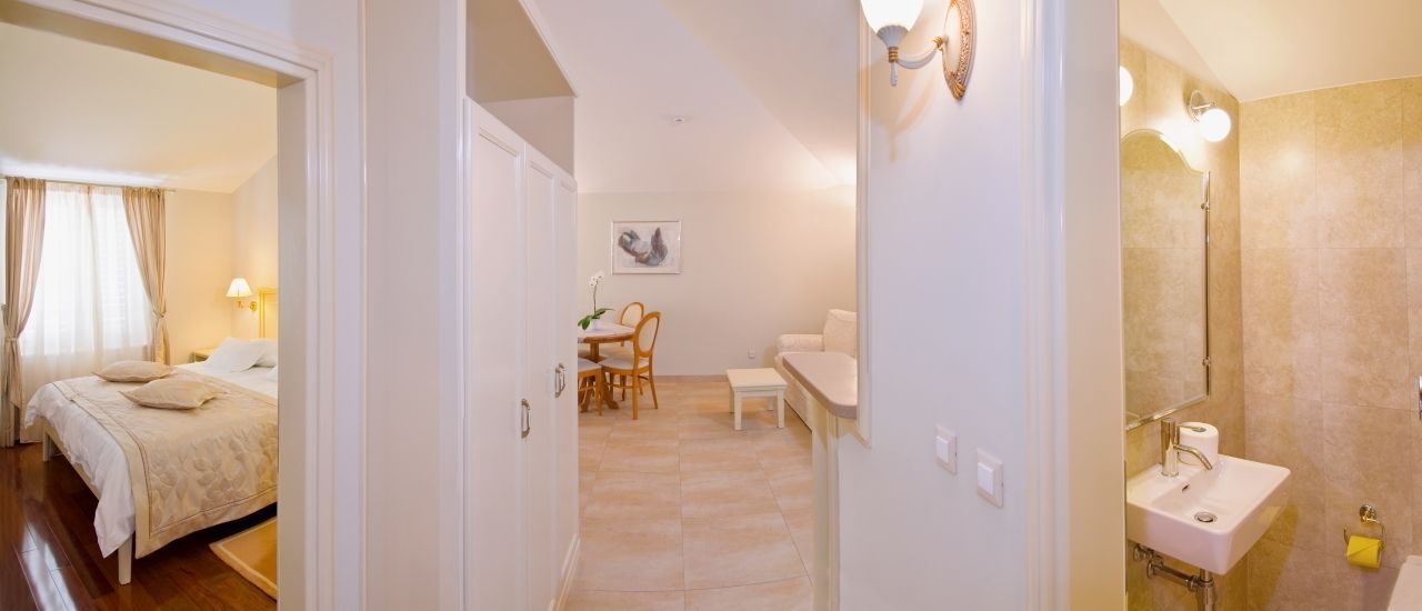 Una habitación de hotel con cama, zona de comedor y baño.