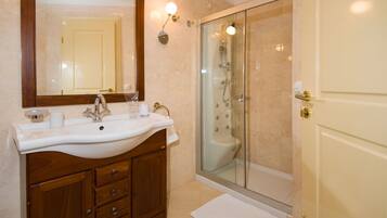 Une salle de bain avec un lavabo blanc, un meuble-lavabo en bois, un grand miroir et une douche à parois de verre.
