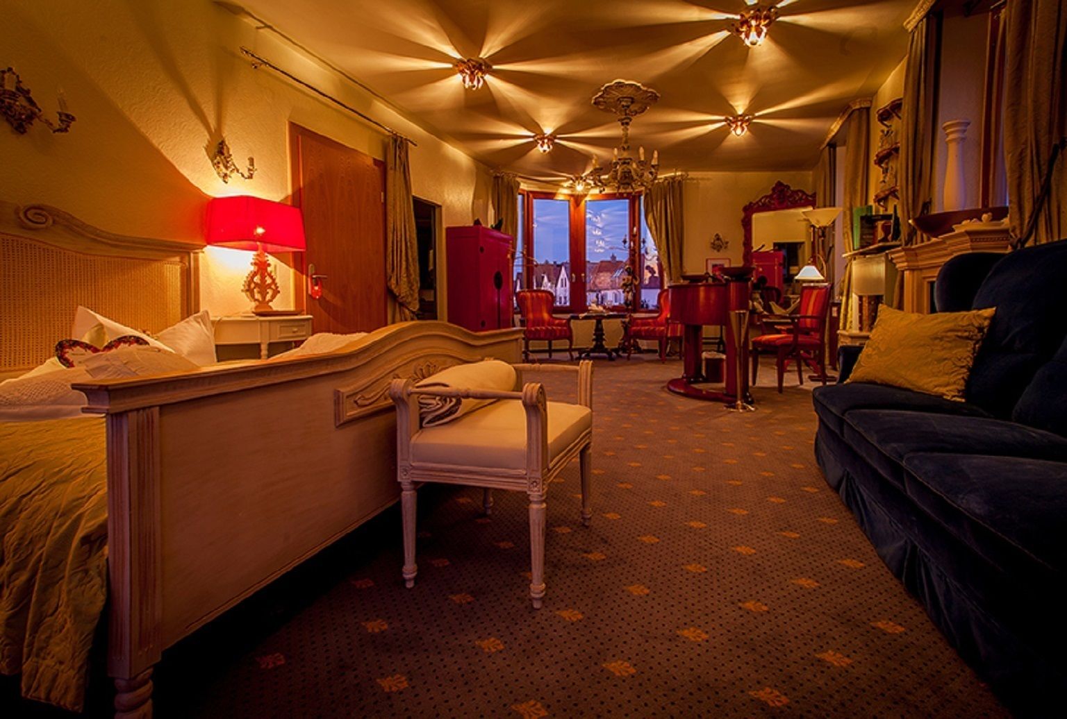 Ein Hotelzimmer mit Bett, Sessel, Sofa, Schreibtisch und Blick auf die Stadt.