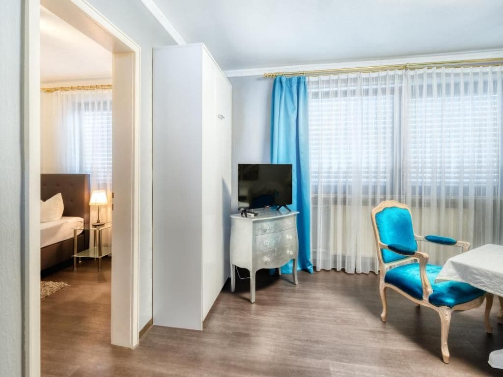 Ein Hotelzimmer mit einem Bett, einem Schreibtisch mit Fernseher, einem Sessel und einem Tisch.