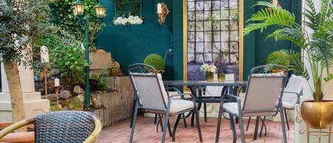 An outdoor patio with a table and chairs, a small waterfall feature, and potted plants.