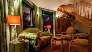 Een kamer met een groene bank, een houten stoel, een klein tafeltje en een trap.
