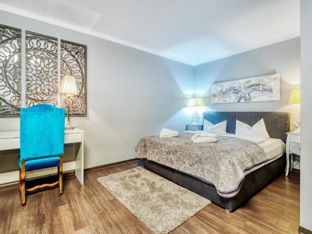 A bedroom with a bed, a desk, a chair, a lamp, and a painting on the wall.