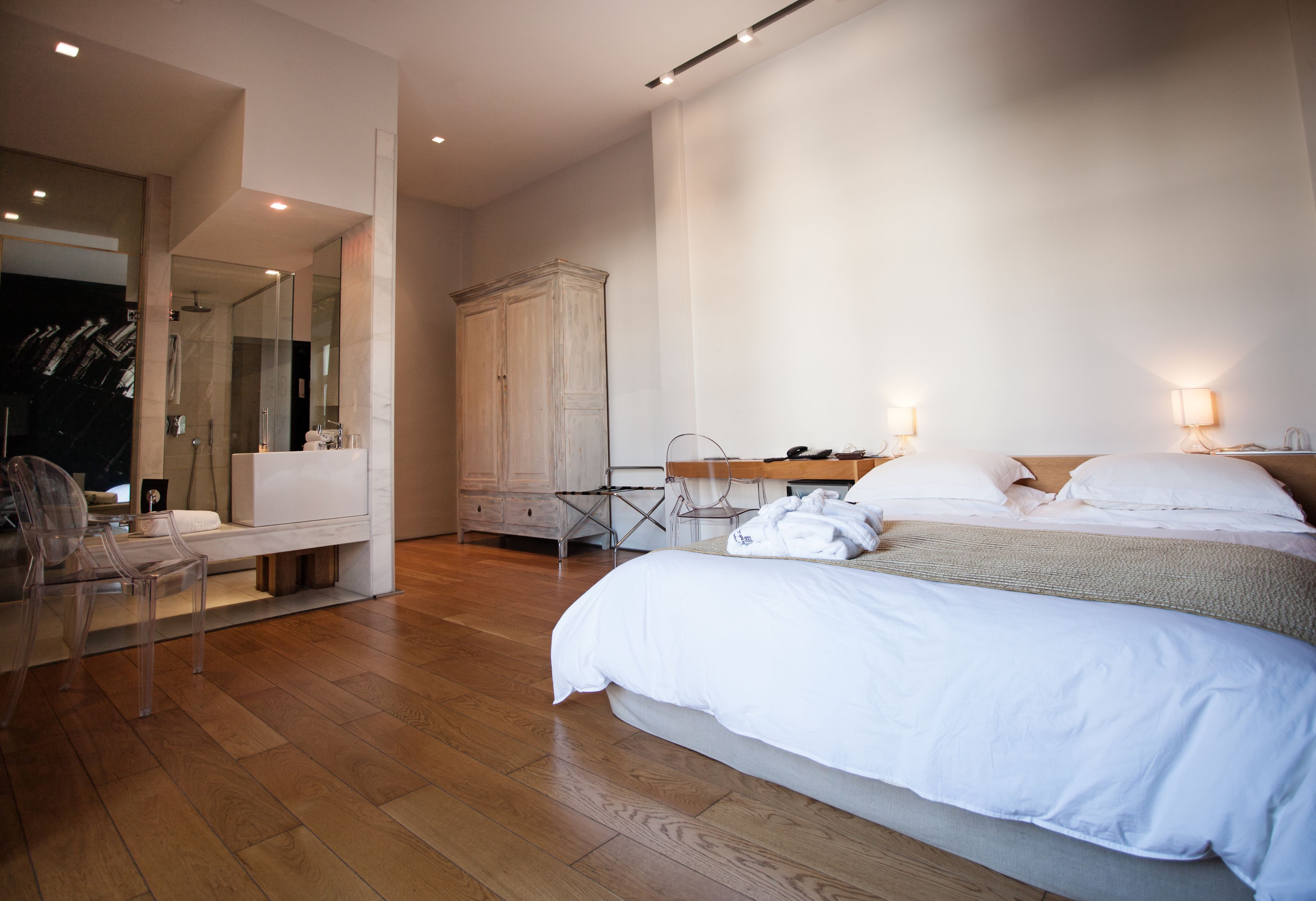 A modern bedroom with a large bed, a wardrobe, a desk, and a chair.