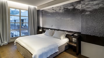 Un dormitorio moderno con una cama grande, vistas de edificios a través de una ventana y una pared con textura.